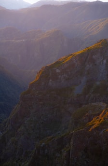 A rugged mountain trail at dawn with soft golden light illuminating the landscape.