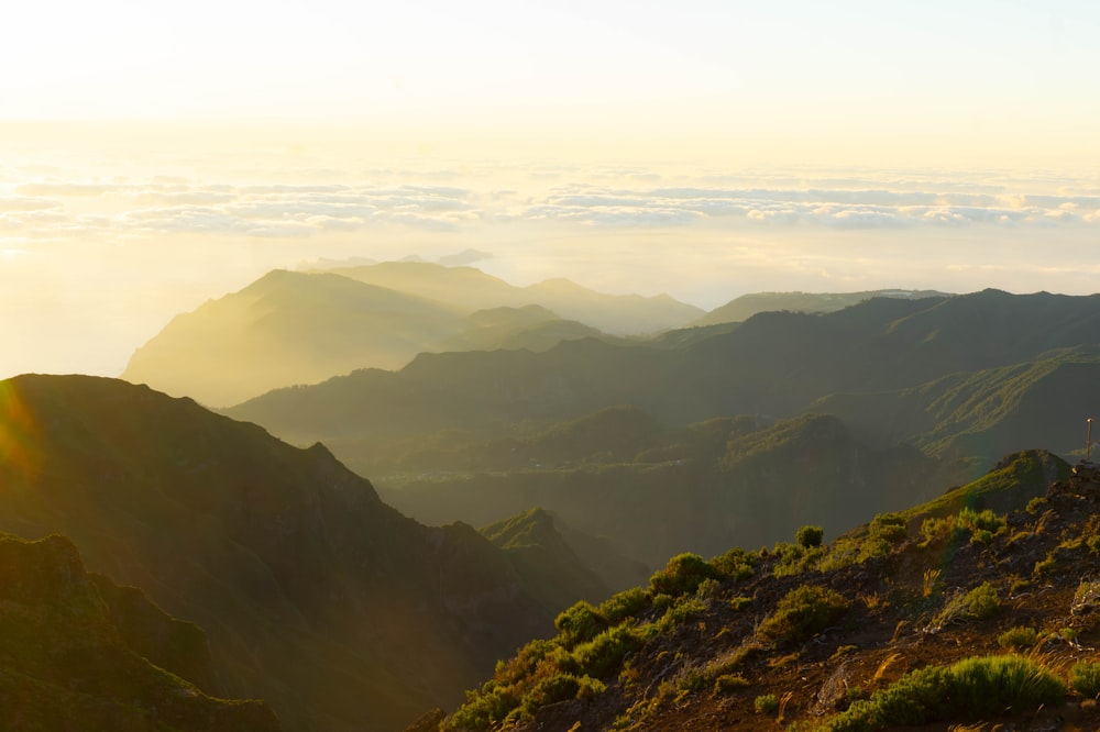 a view of a mountain range with the sun shining through the clouds