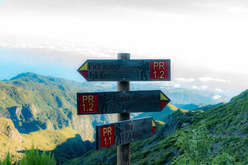 a wooden sign pointing in different directions on a mountain