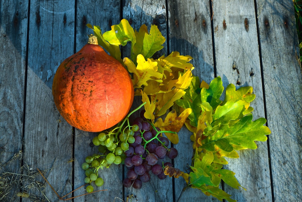 a pumpkin and some grapes on a wooden table