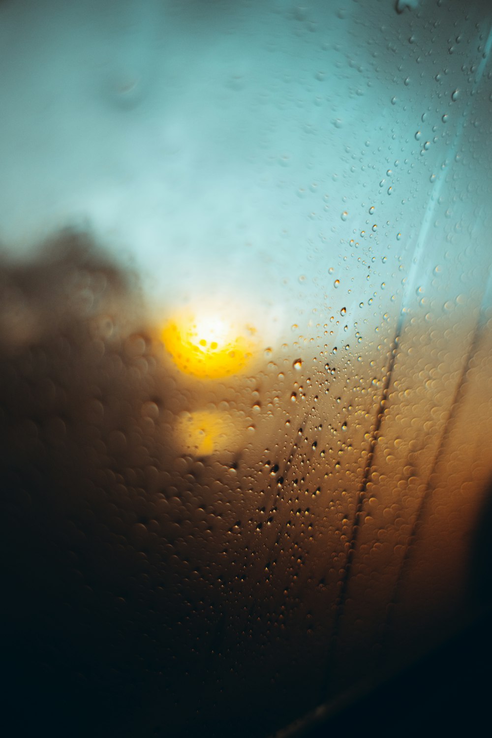 a view of the sun through a rain covered window