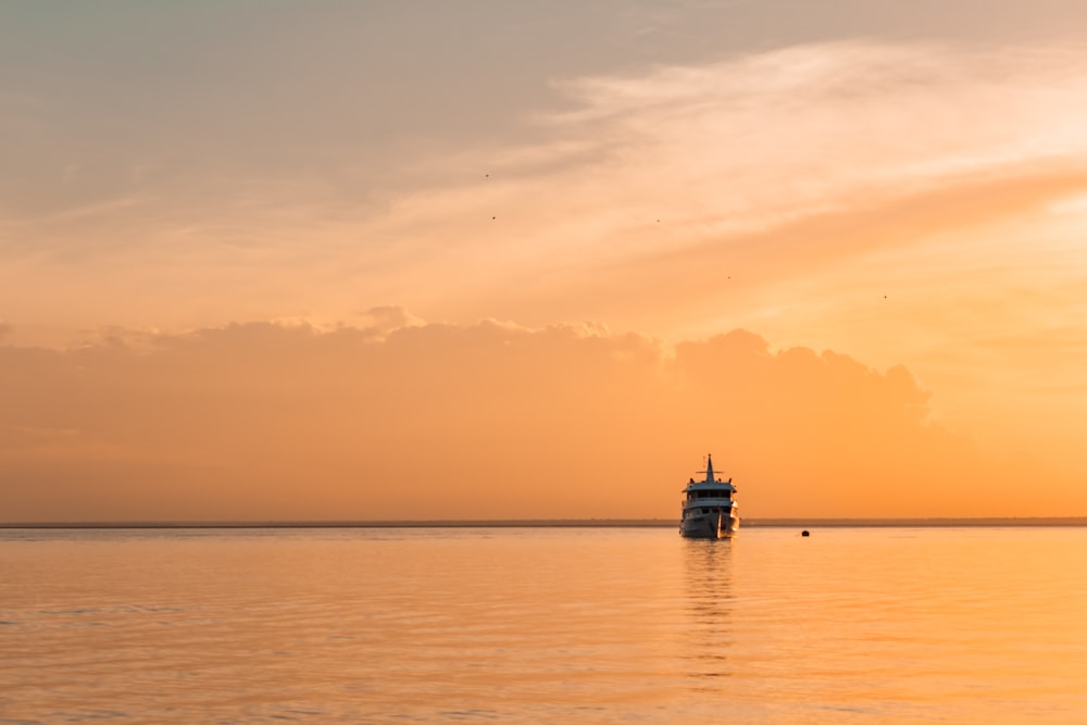 Un bateau est sur l’eau au coucher du soleil