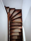 Historic staircase leading up to the attic apartment, with warm wooden steps and handrails.