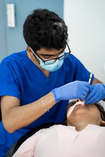 a man in a blue shirt is getting his teeth checked