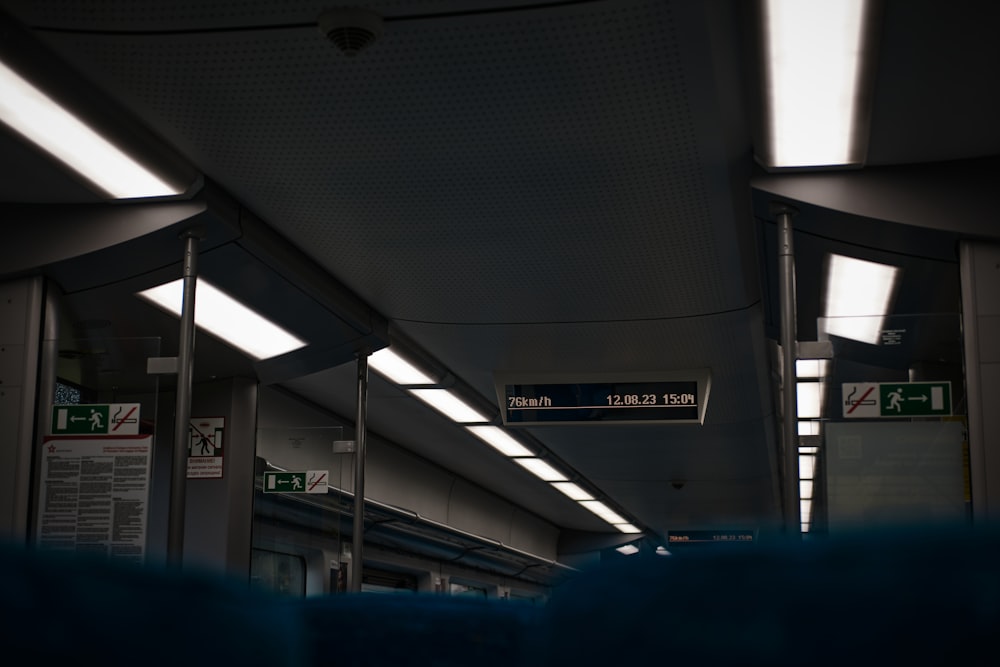 a train station with signs and lights on the ceiling