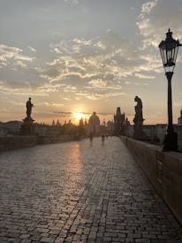 The Charles Bridge at sunrise with soft light falling on ancient stones and quiet water.