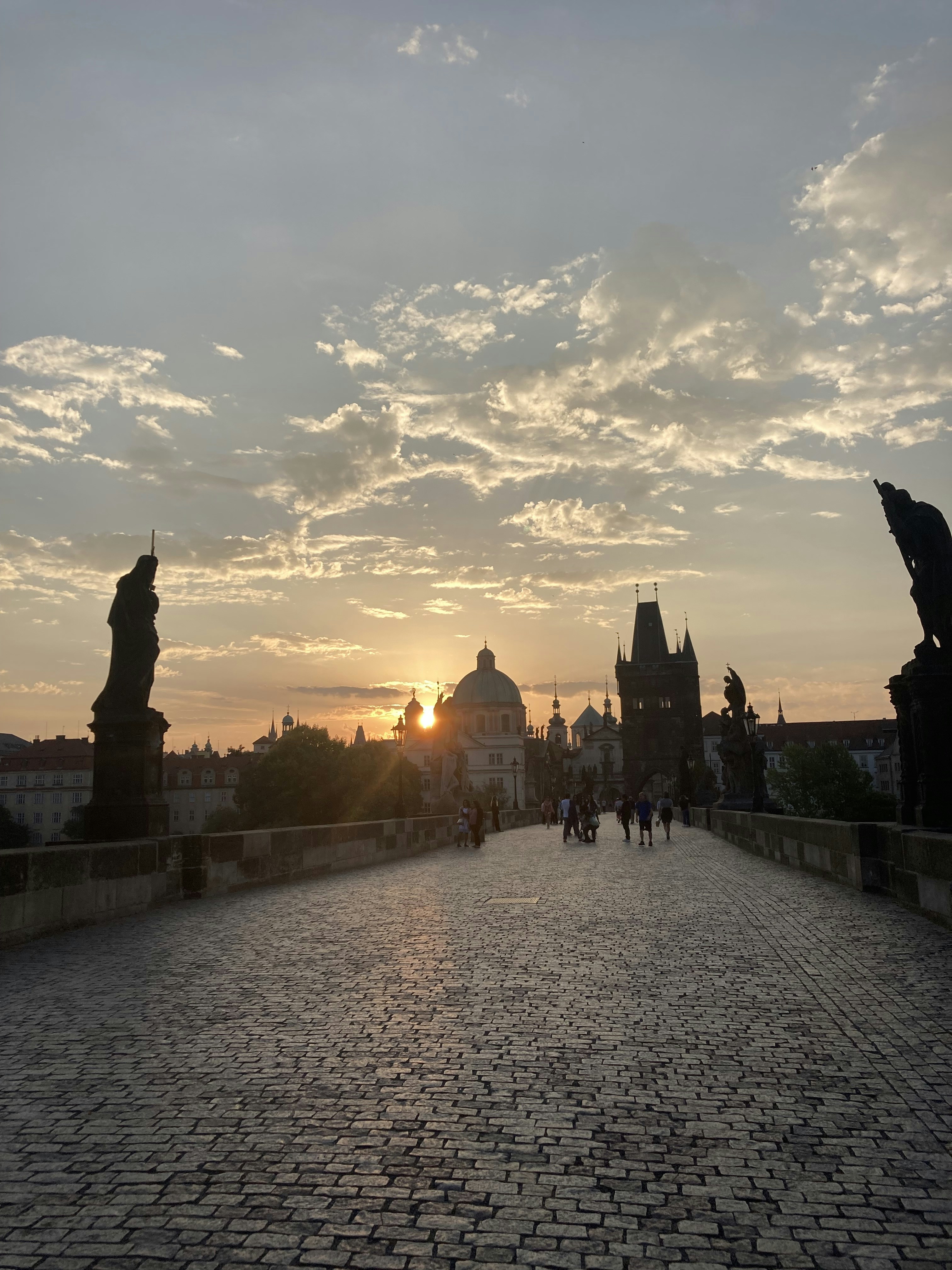 Puente Carlos de Praga al amanecer con estatuas de santos, río Moldava y torres del casco antiguo al fondo