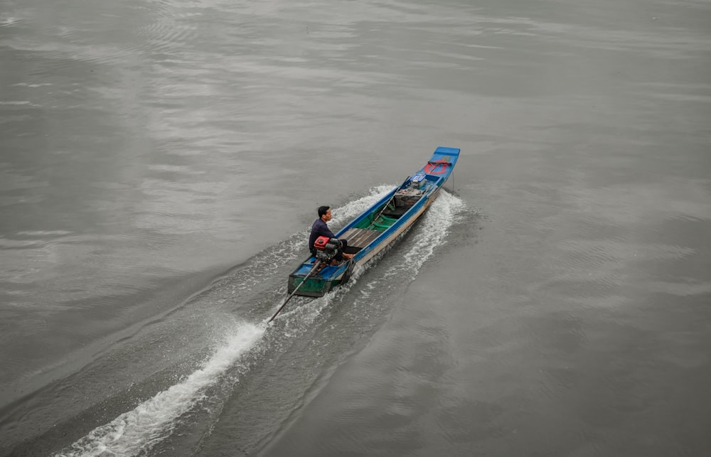 a man riding on the back of a blue boat