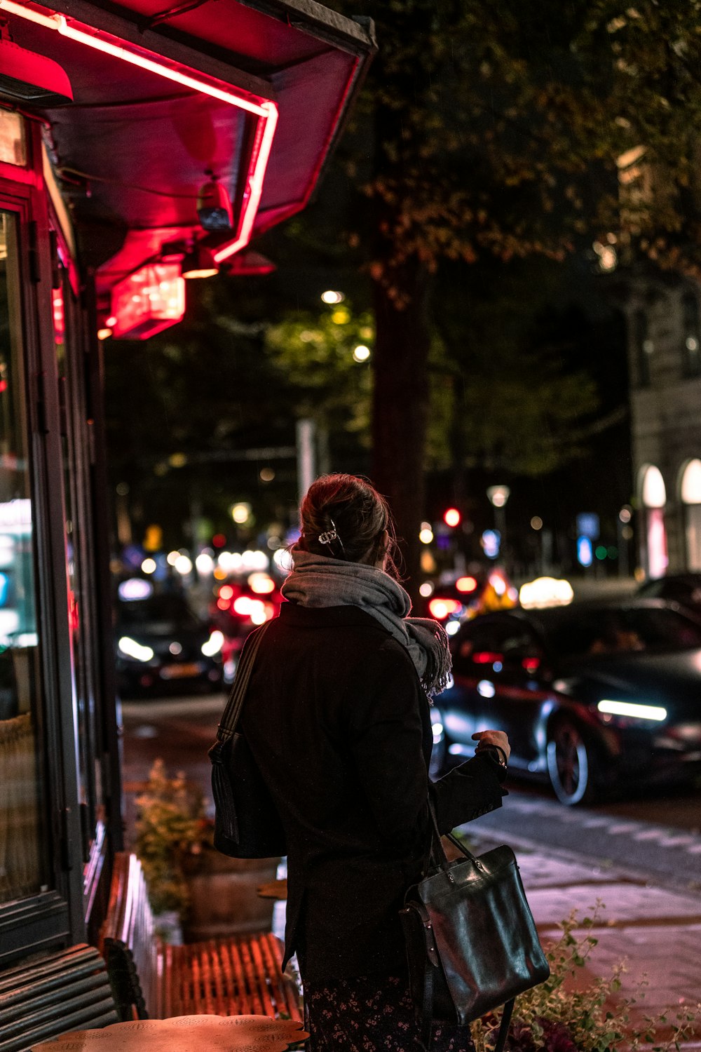 a woman is waiting at a bus stop at night