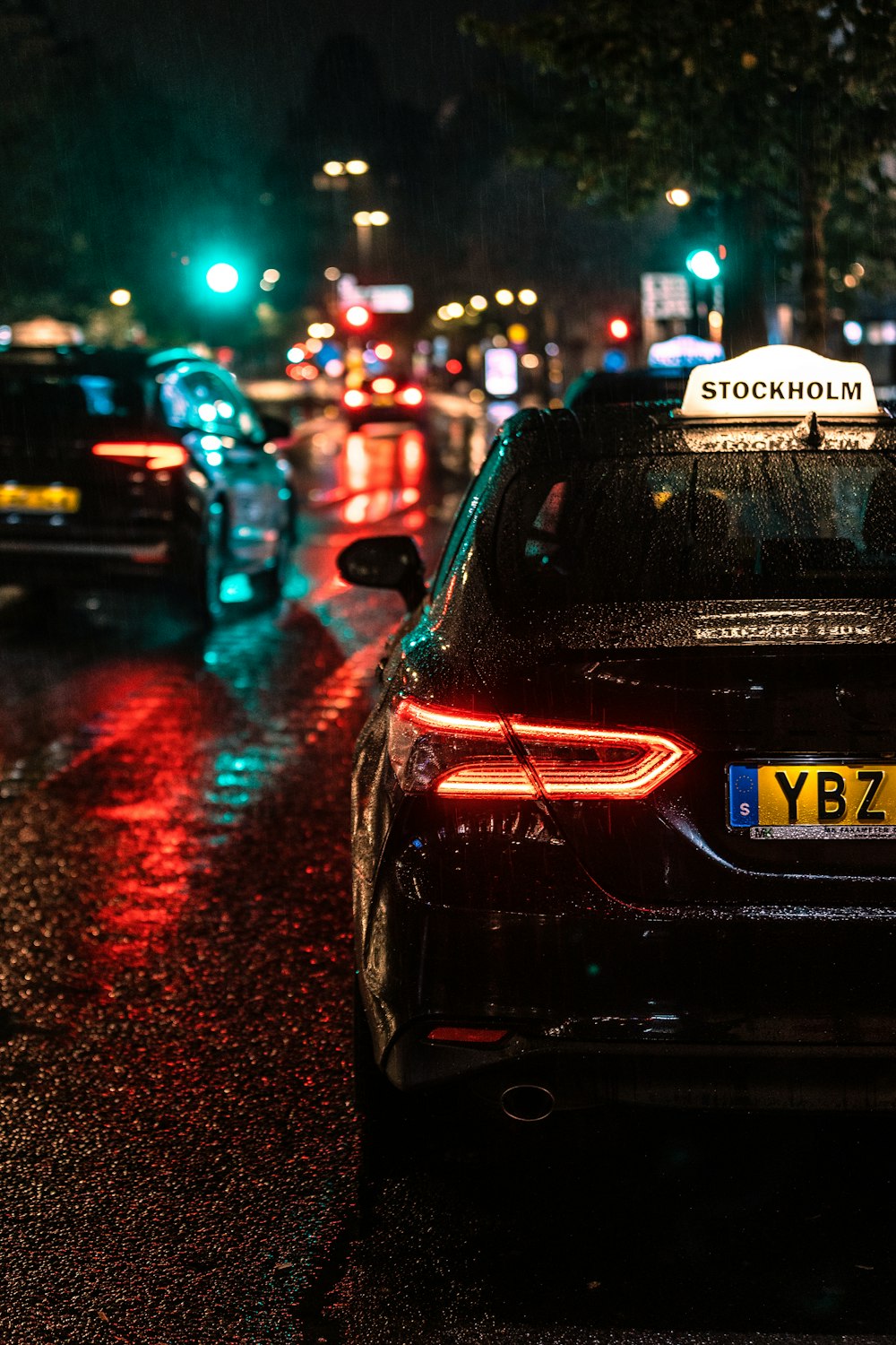 a city street at night with cars parked on the side of the road