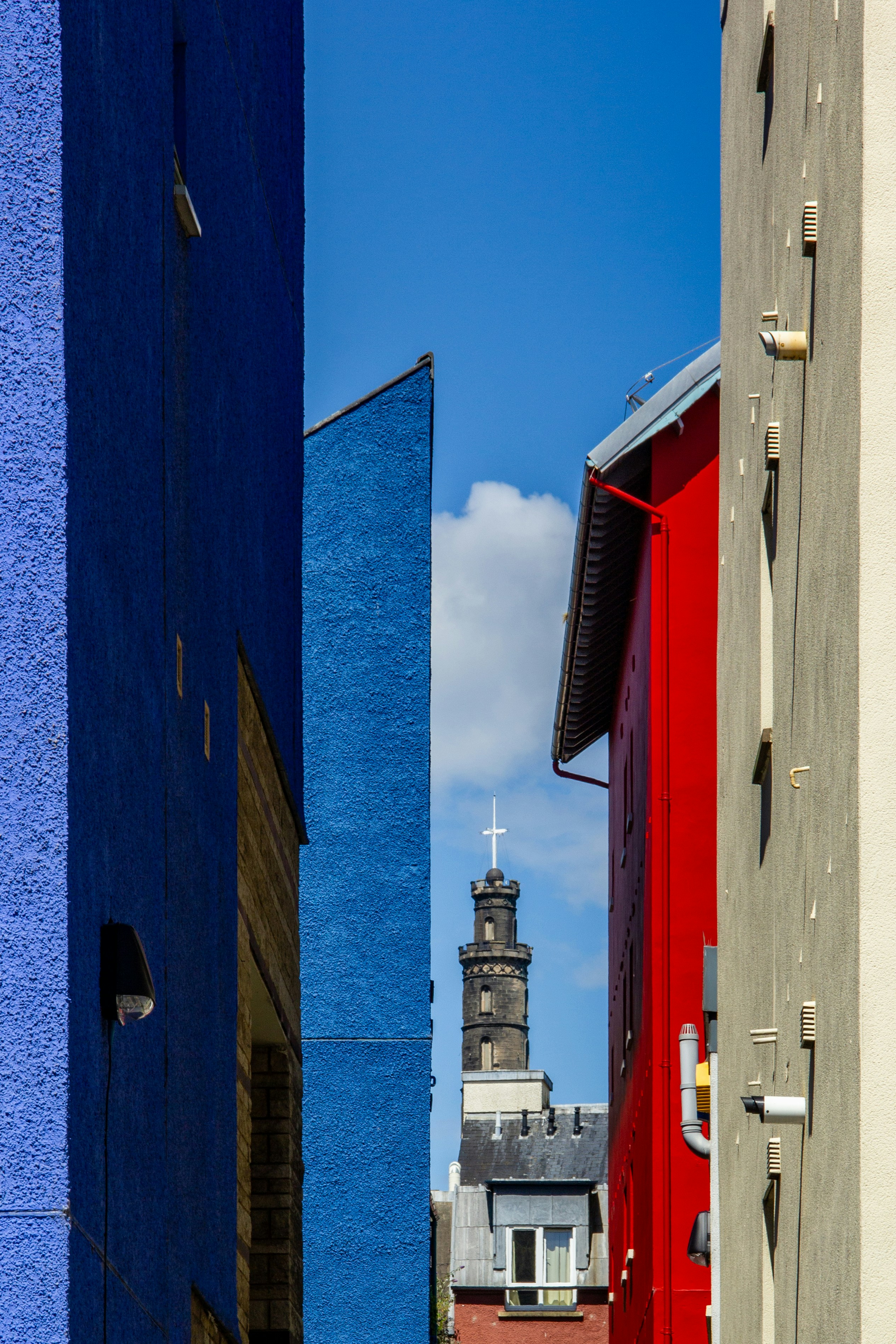 a narrow street with a church steeple in the background