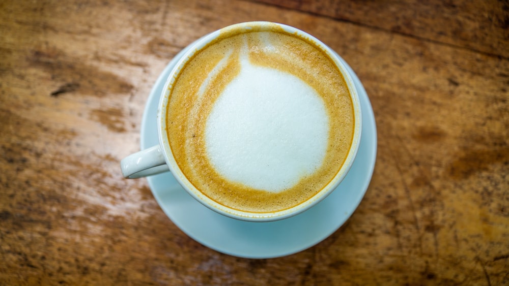 a cup of cappuccino sitting on top of a wooden table