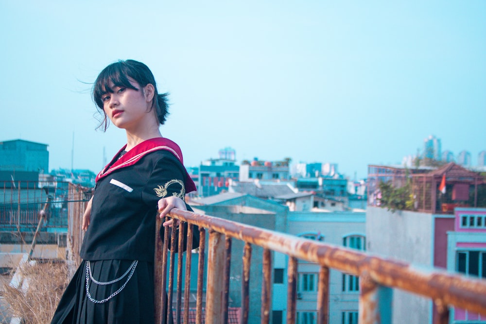 a woman standing on a balcony with a city in the background