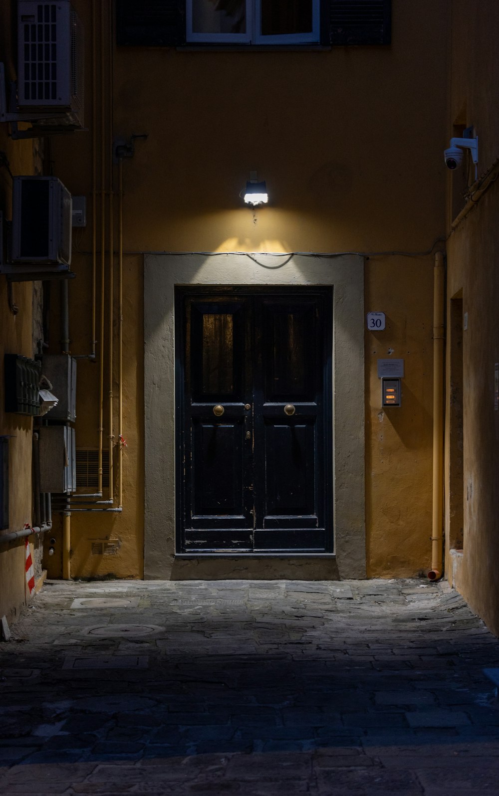 a dark alleyway with two doors and a light on