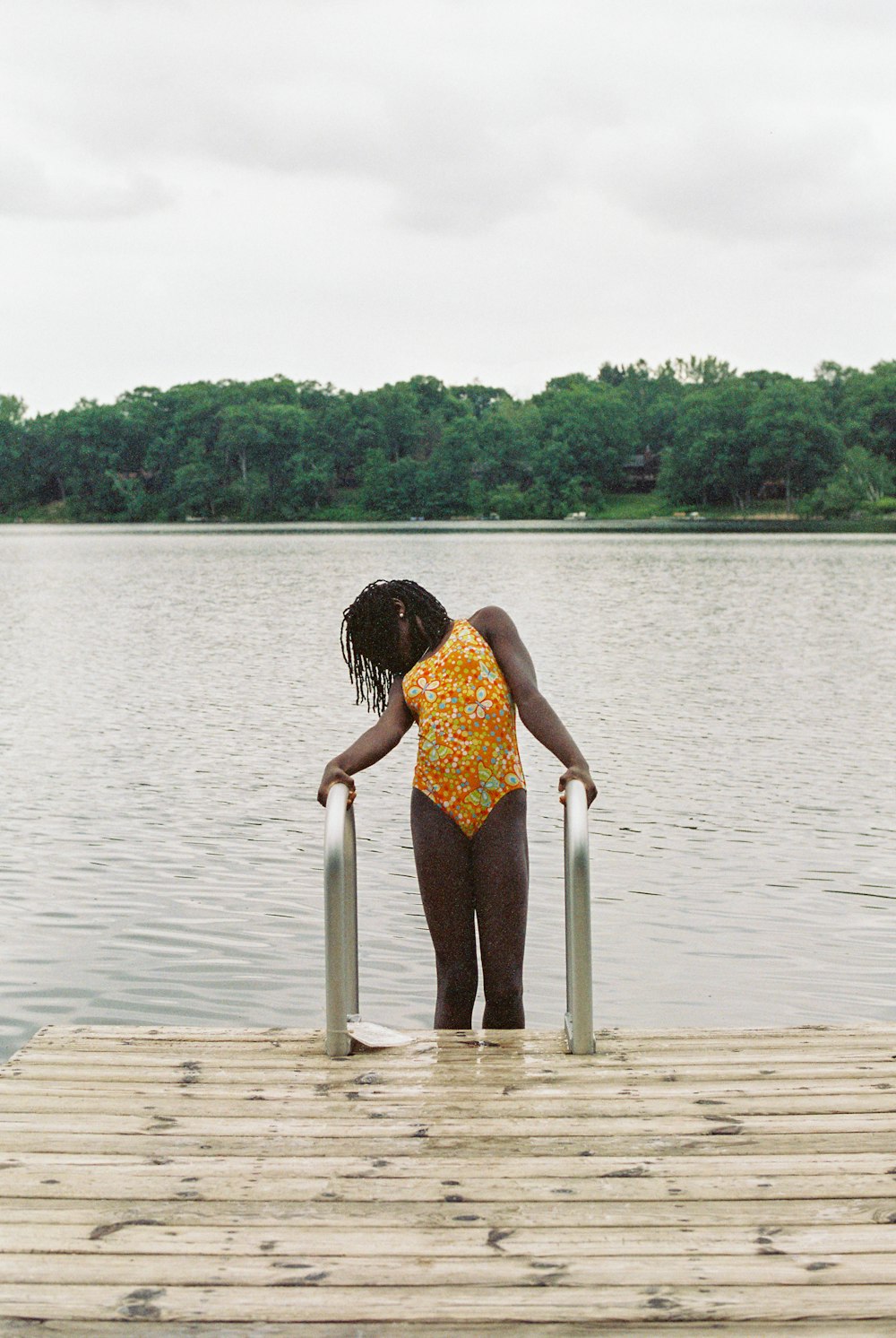 a woman standing on a dock next to a body of water