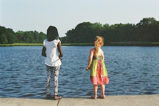 a couple of people that are standing in front of a body of water