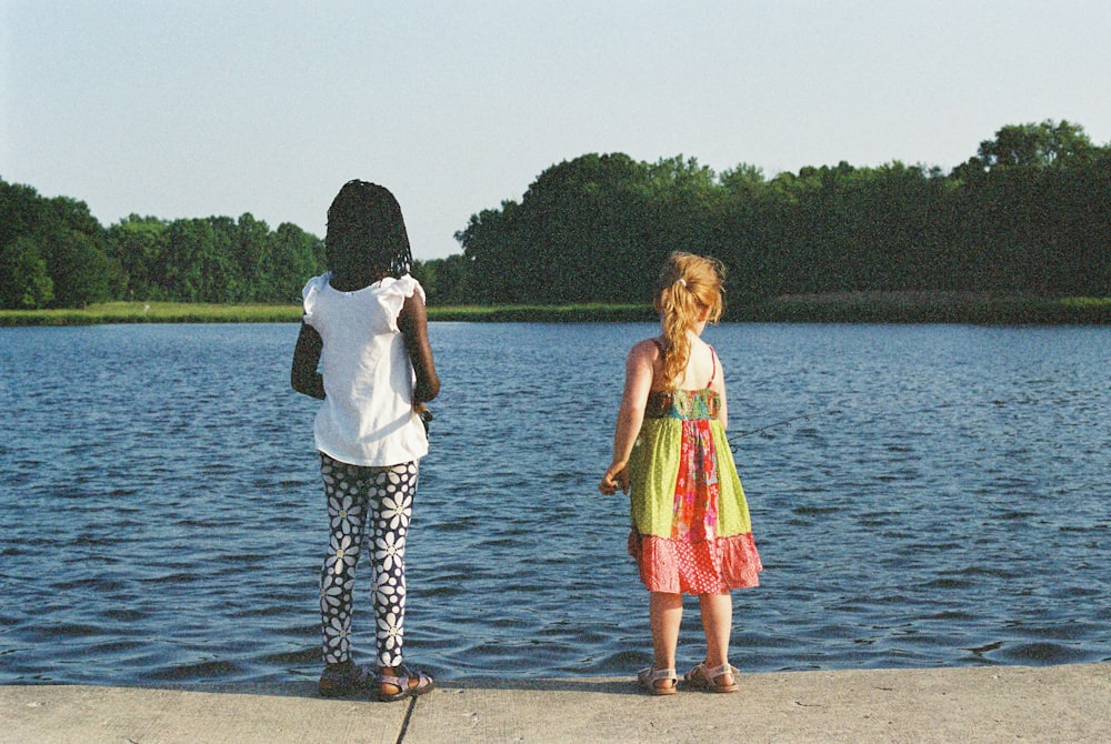 a couple of people that are standing in front of a body of water