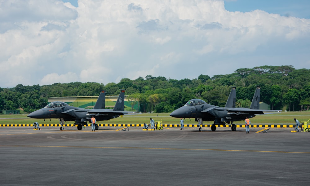 a couple of fighter jets sitting on top of an airport tarmac