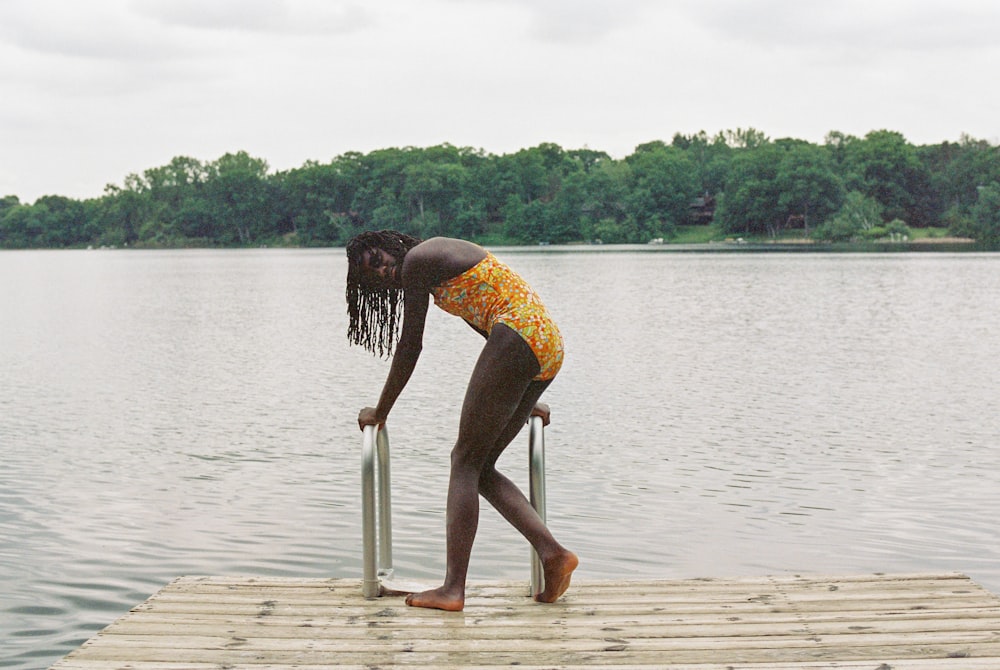 a woman standing on a dock next to a body of water
