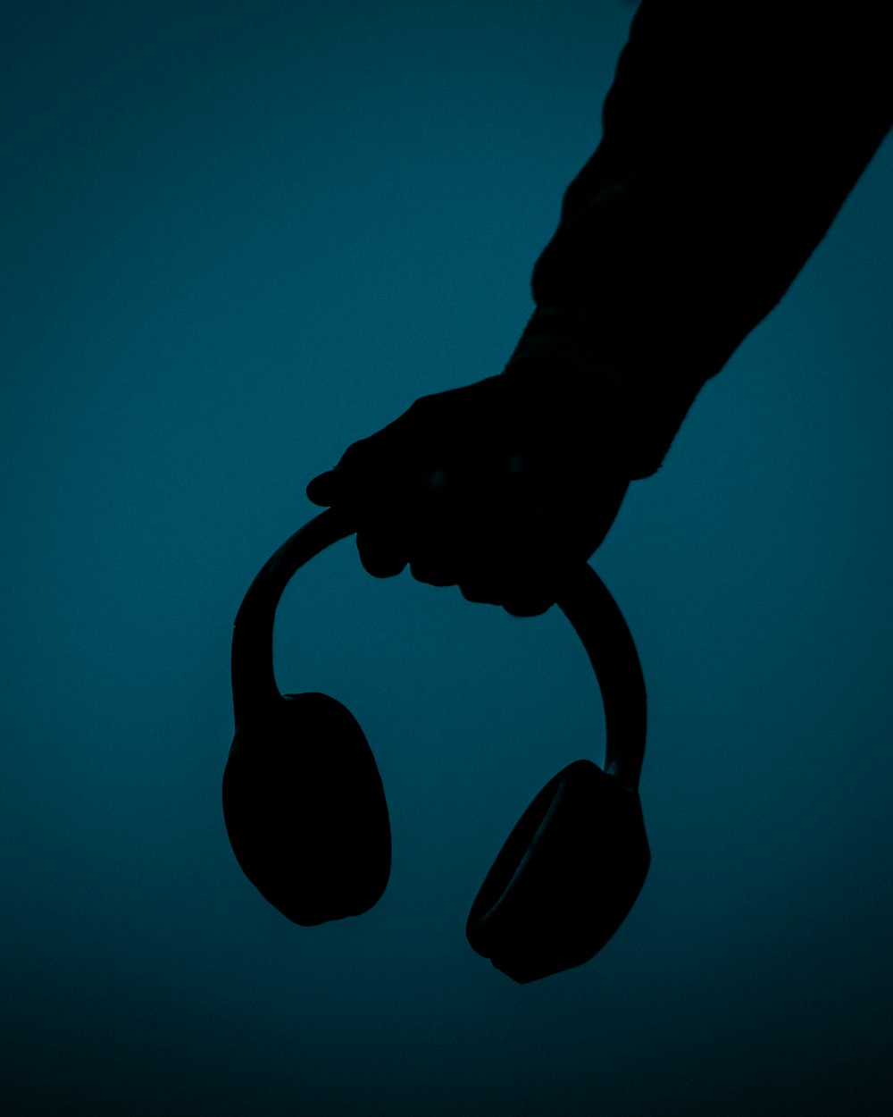 a silhouette of a person holding a pair of headphones