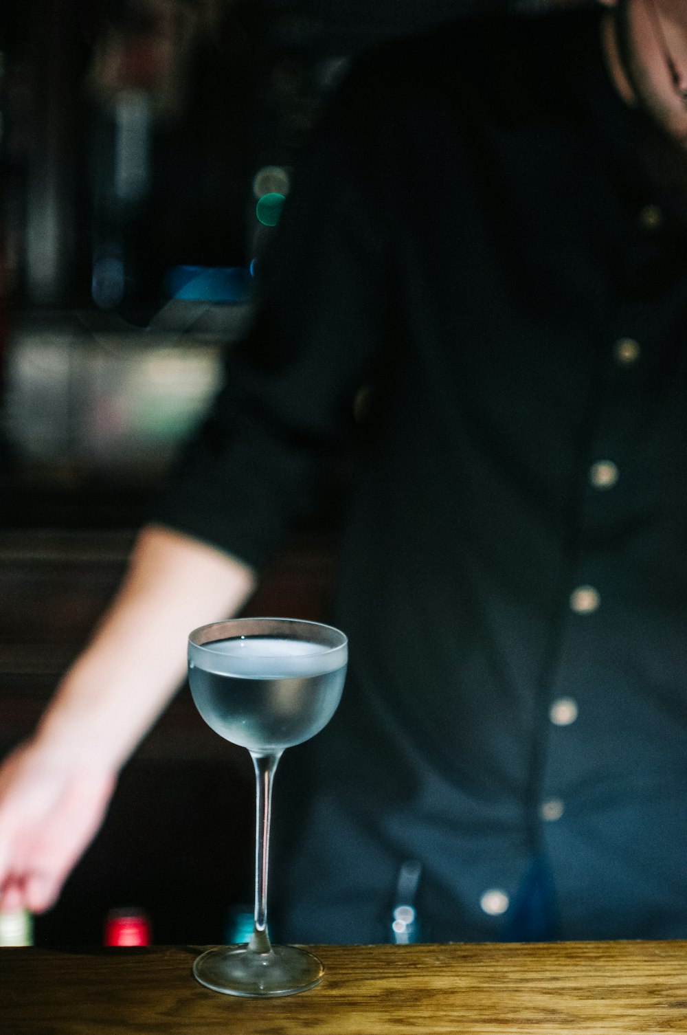 a person behind a bar with a drink in a glass