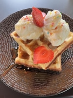Smiling children enjoying their warm waffles with whipped cream and sprinkles on a sunny day