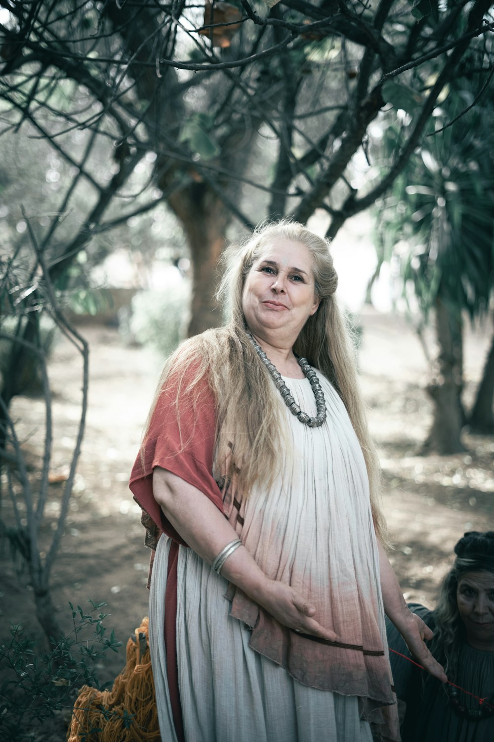 a woman in a white dress standing under a tree