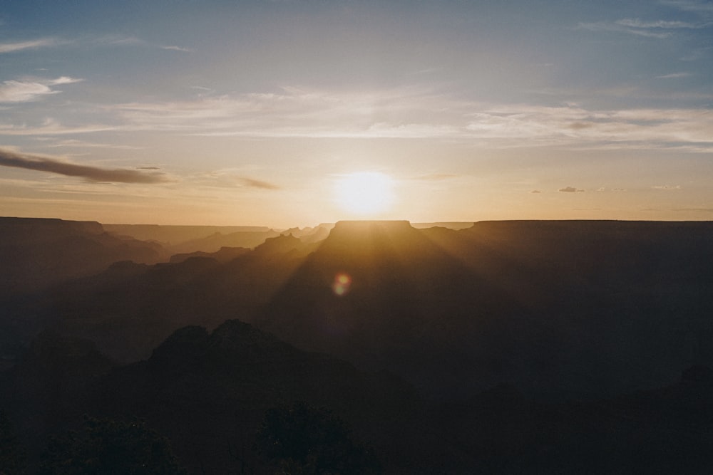 the sun is setting over a mountain range