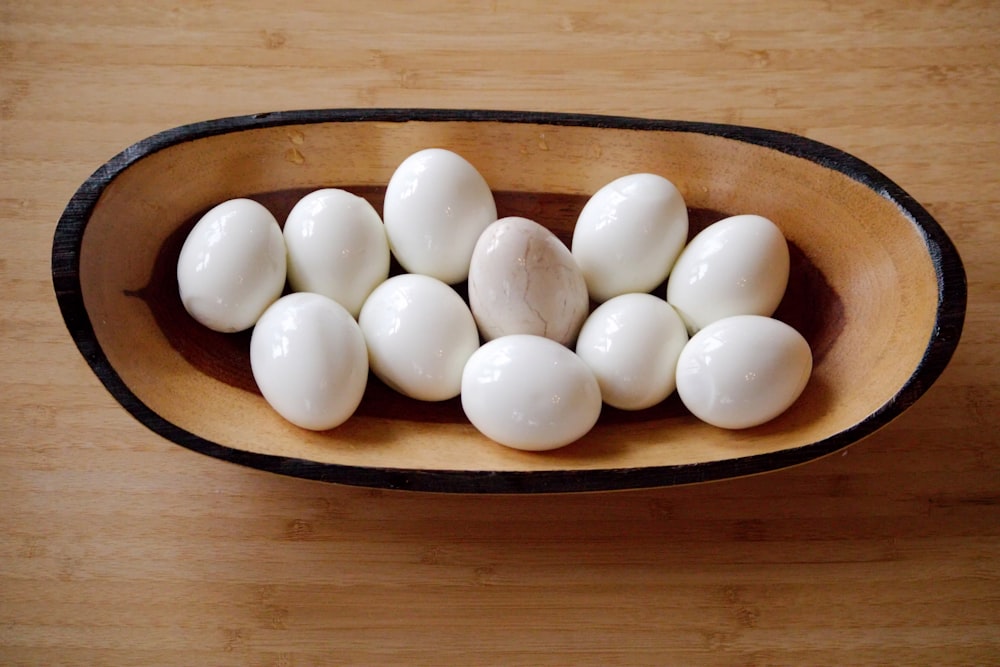 나무 탁자 위에 흰 달걀로 채워진 나무 그릇