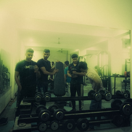 A group of motivated athletes training together with weights and footballs in a bright, energetic space.