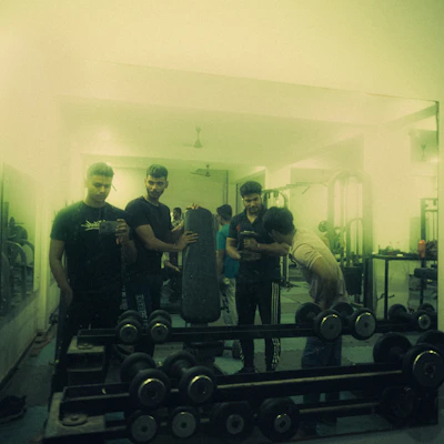 A group of students lifting weights together in a bright gym filled with motivational posters.