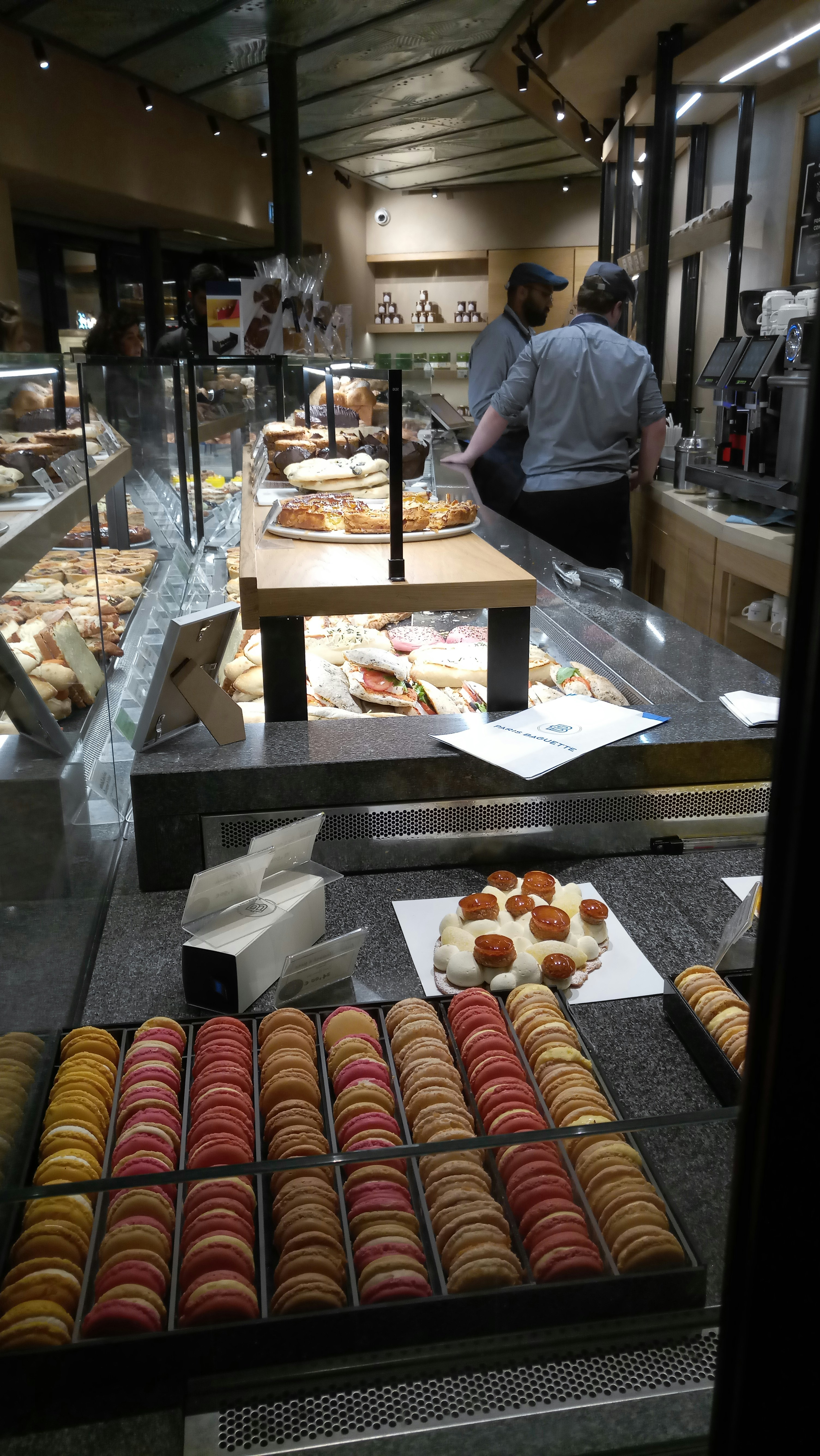 Parisian patisserie counter with macarons, mustard jars, and elegant packaging in soft morning light