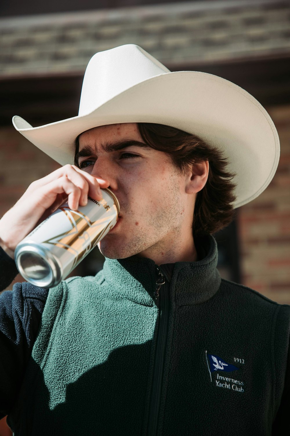 Un hombre con sombrero de vaquero bebiendo de un vaso