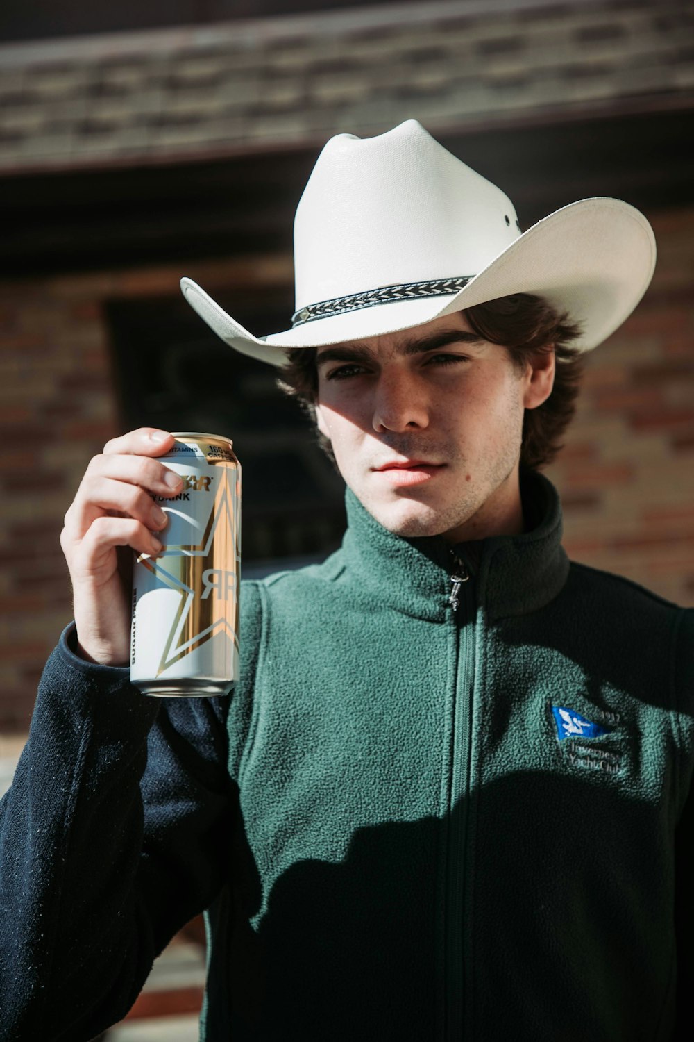 a man in a cowboy hat holding a can of beer