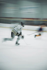 Dynamic image of a hockey stick striking the puck, captured mid-action with a blurred background emphasizing speed.