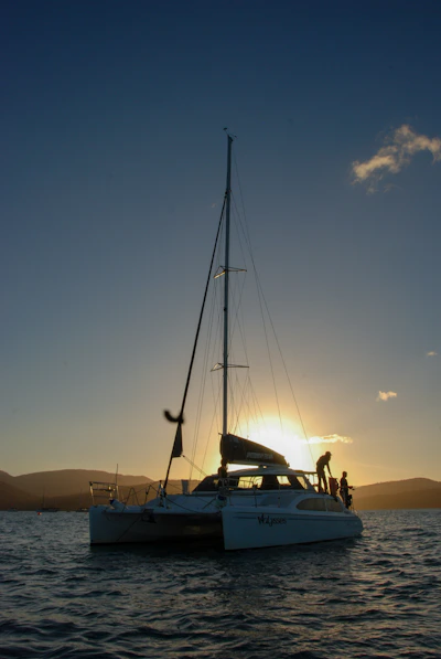 the sun is setting on a sailboat in the water