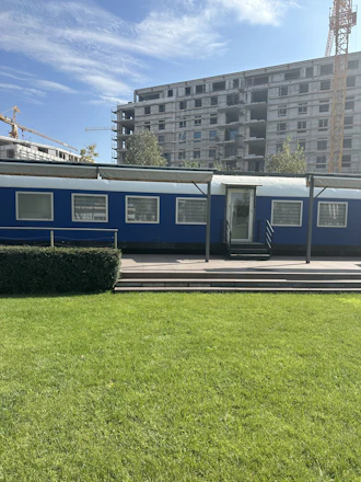 A sleek, steel-gray portable cabin set up on a construction site under a clear blue sky.