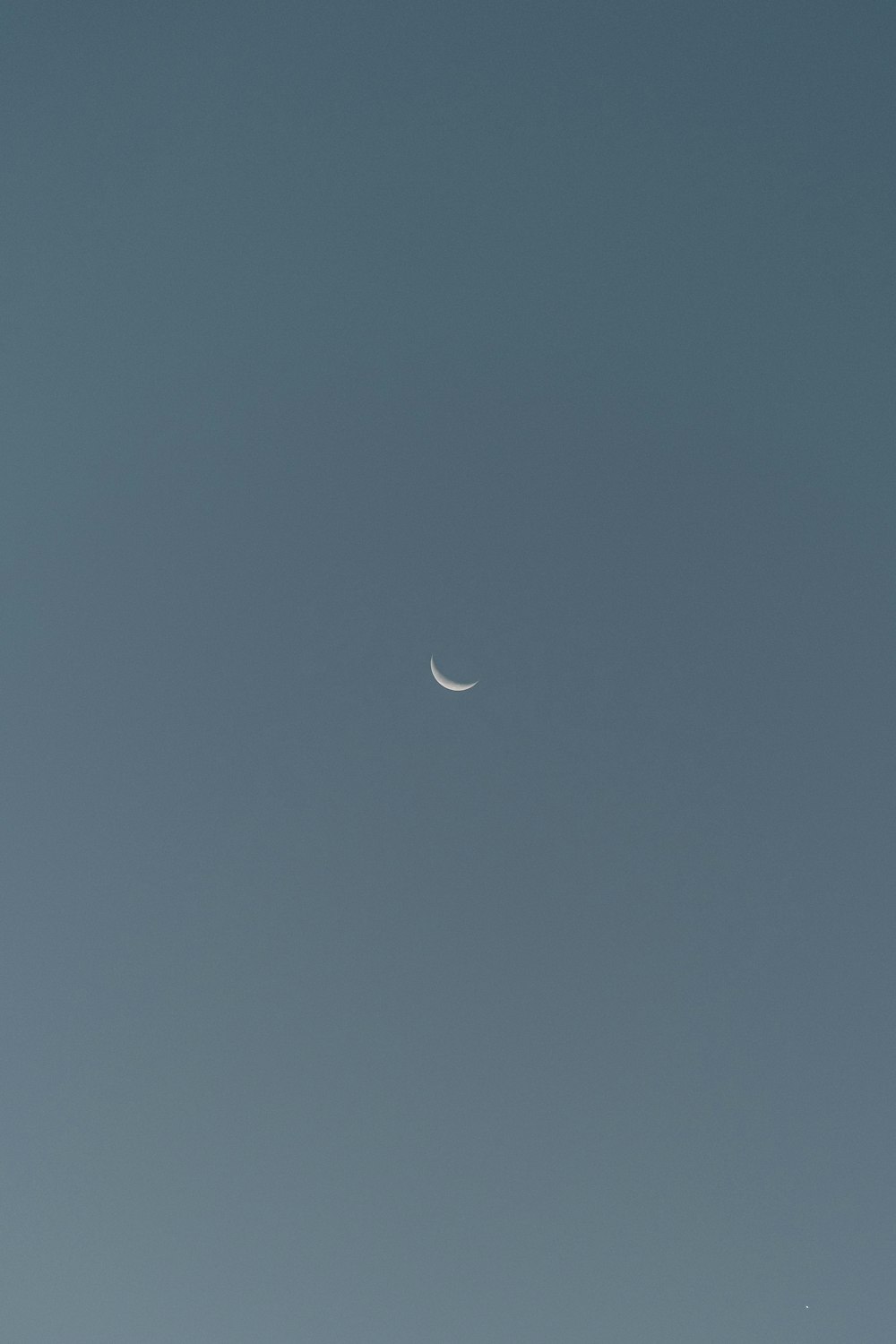 a plane flying in the sky with a half moon
