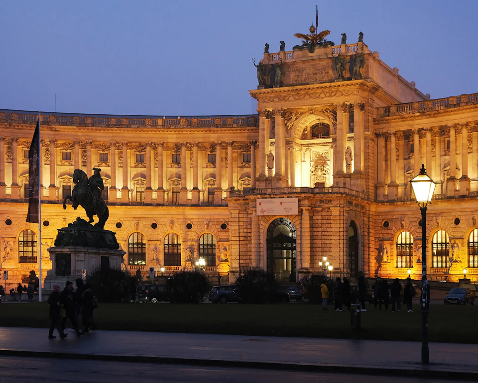 Grand, ornate building with large dome and columns stands against clear blue sky at dusk