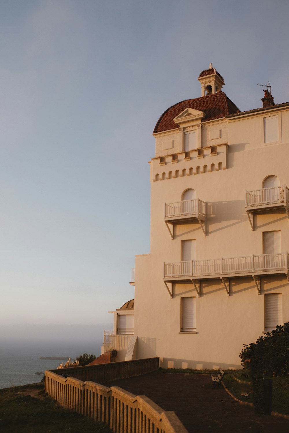 a tall white building with a brown roof