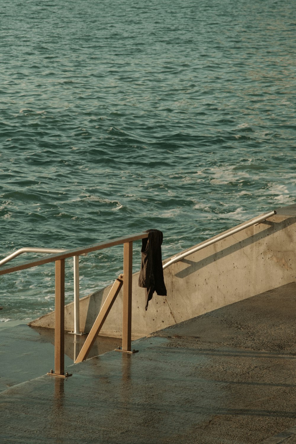 a person sitting on a railing next to the ocean