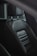 A close-up view of a car seat made of dark leather. The seat has detailed stitching and is equipped with a headrest supported by two metal rods. The sleek surface of the leather reflects light, emphasizing its texture and quality.