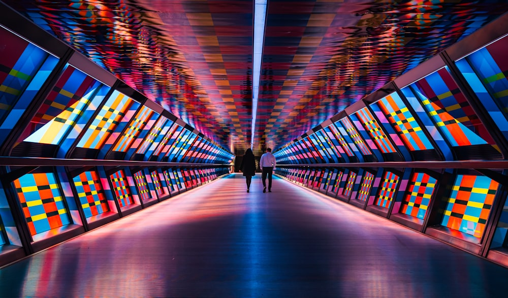 a person walking down a walkway with colorful lights on it