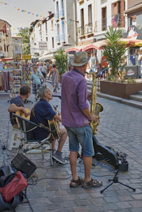 A lively street scene with a small acoustic band playing outdoors as a diverse crowd listens and enjoys the music.