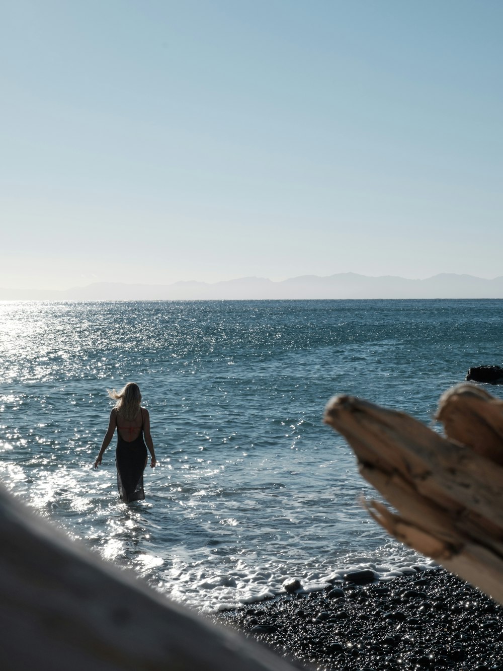 a woman wading in the ocean on a sunny day