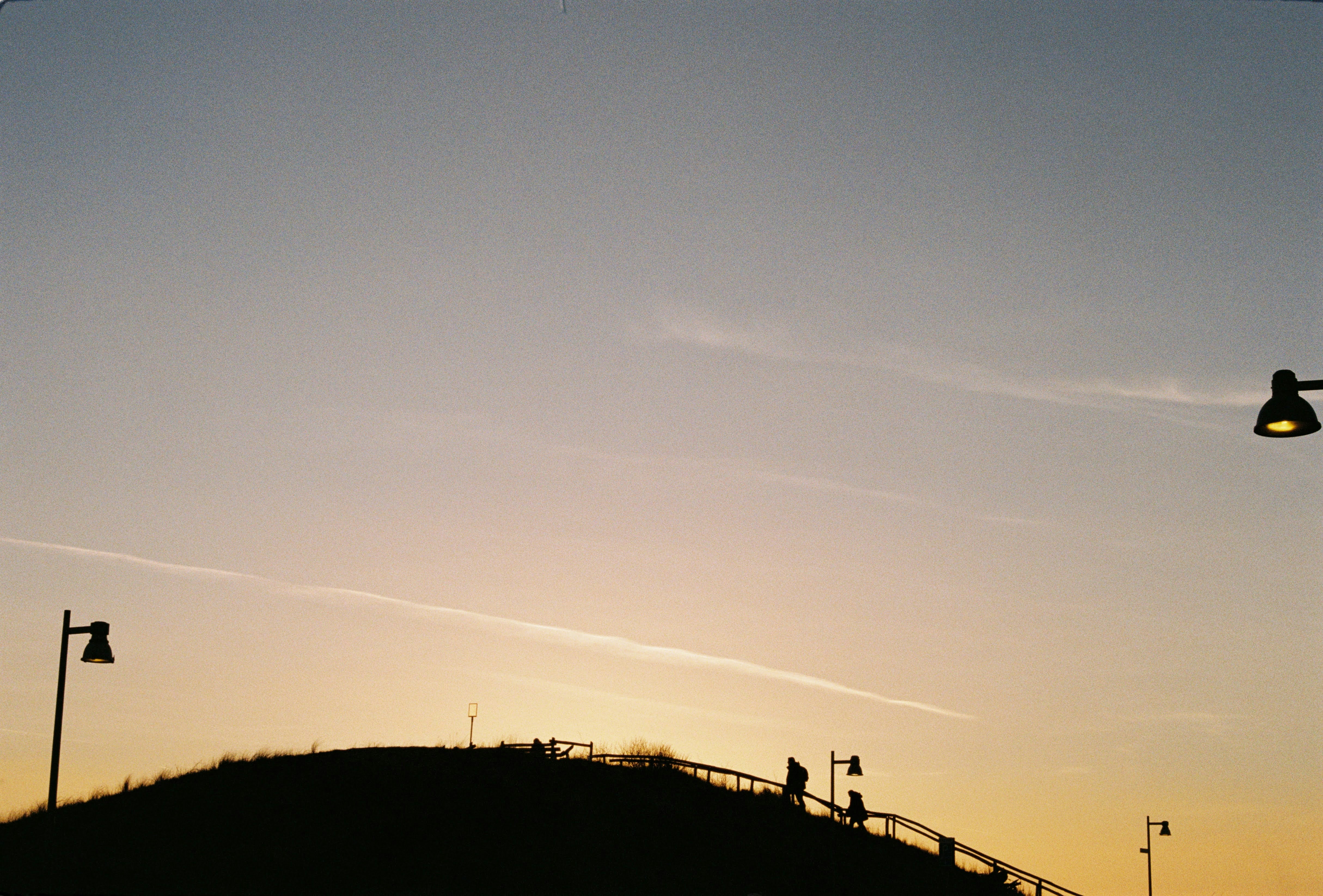 صورة ظلية لخريج يقذف قبعته في الهواء عند غروب الشمس.