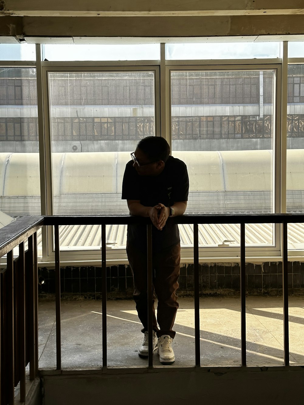 a person leaning against a railing in front of a window