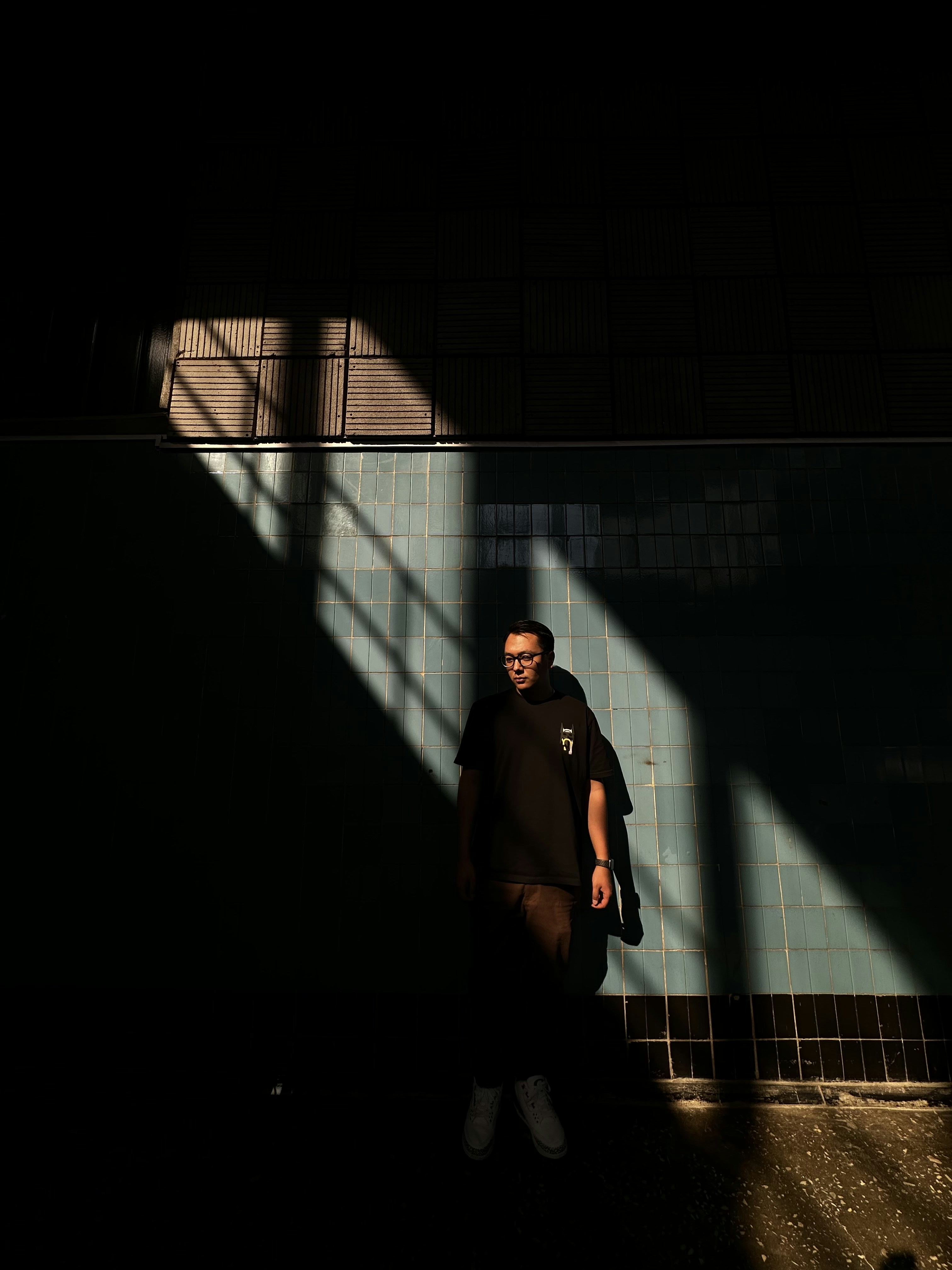 a man standing in the shadows of a building