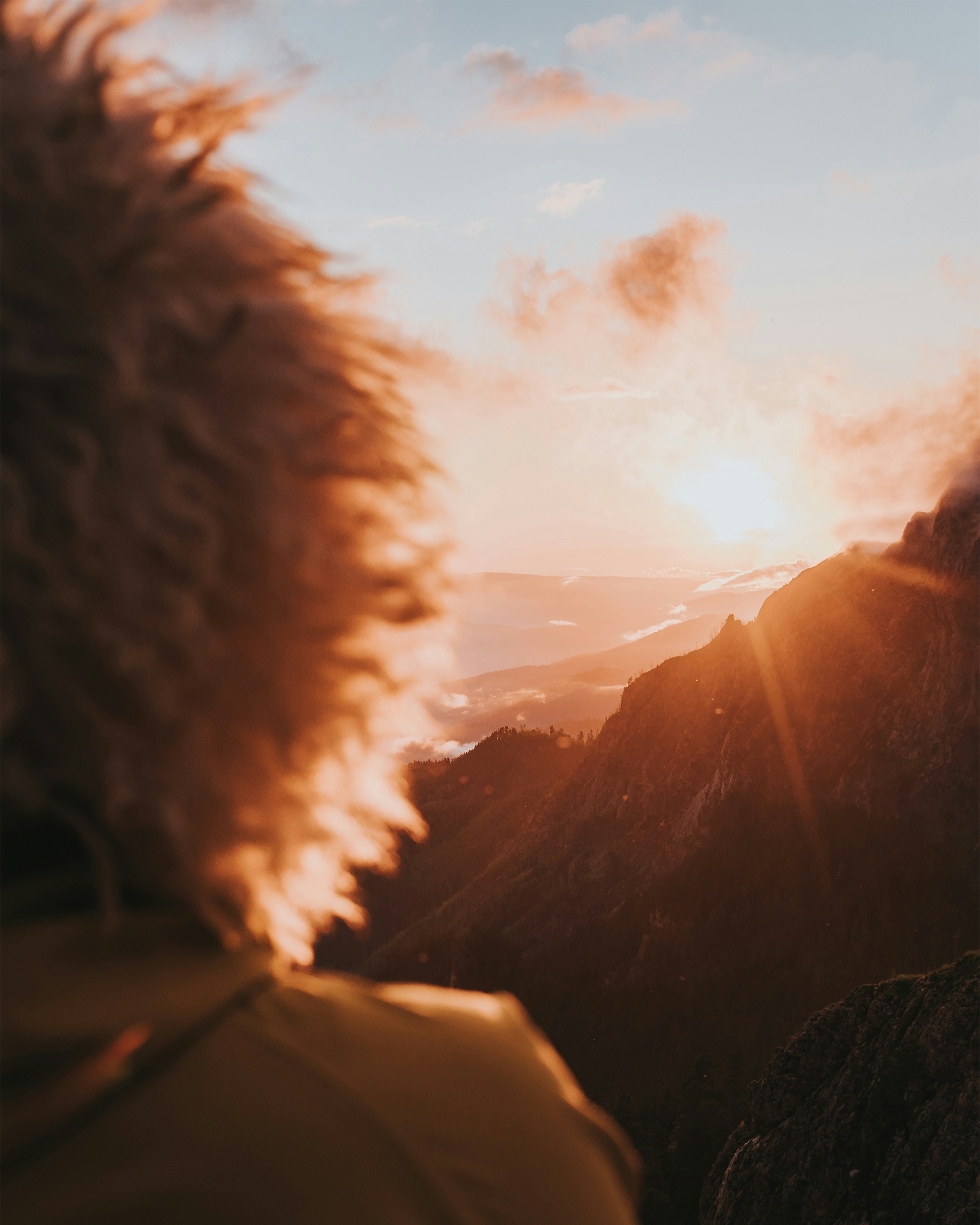a person standing on top of a mountain looking at the sun