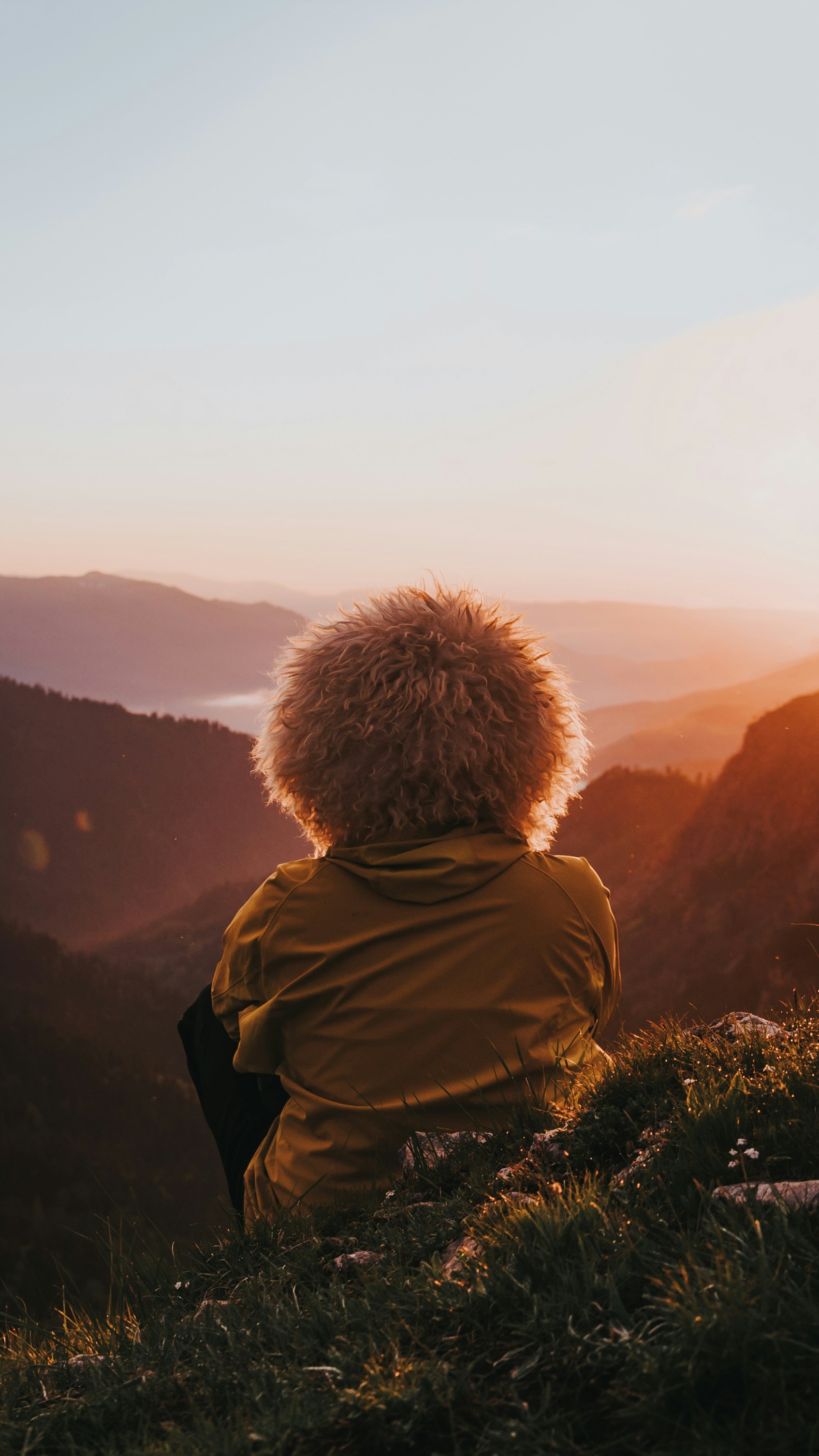 a person sitting on top of a grass covered hill